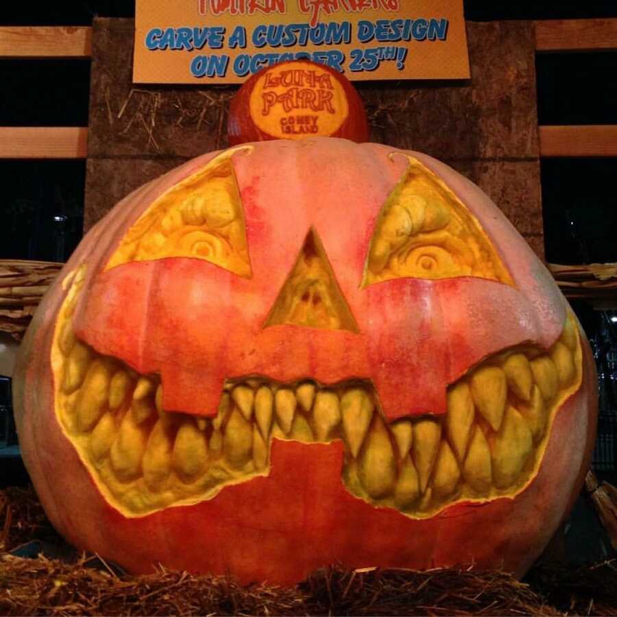 Giant pumpkin sculpture of a Jack-O-Lantern face at Luna Park contest, created by Maniac Pumpkin Carvers. 