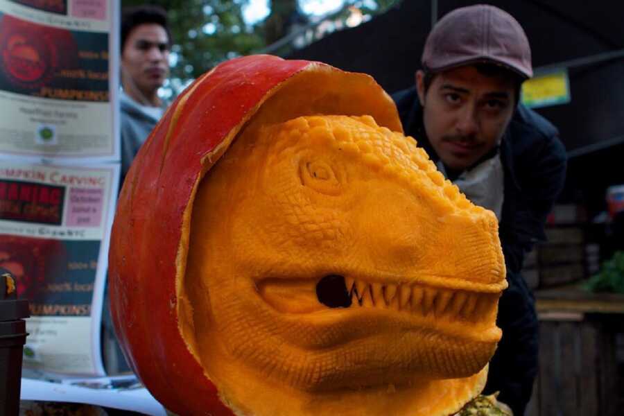 Large pumpkin sculpting of a dinosaur head, created by Maniac Pumpkin Carvers. 