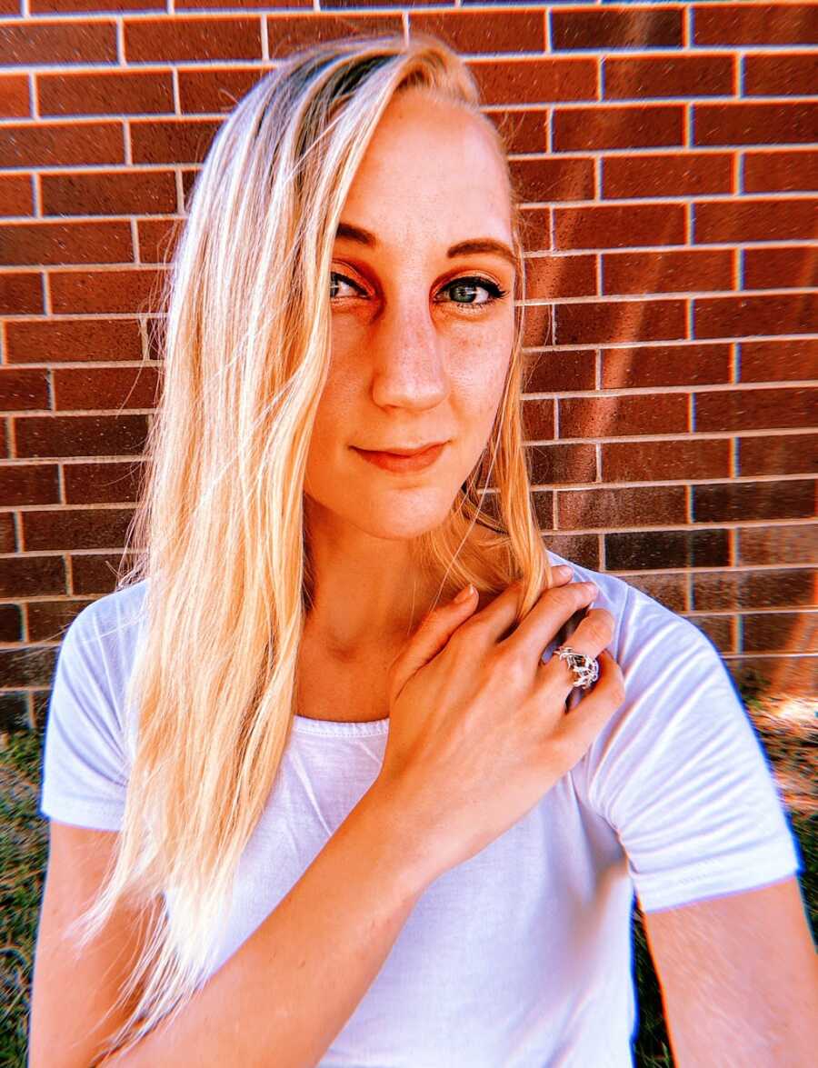 A woman with anorexia in front of a brick wall