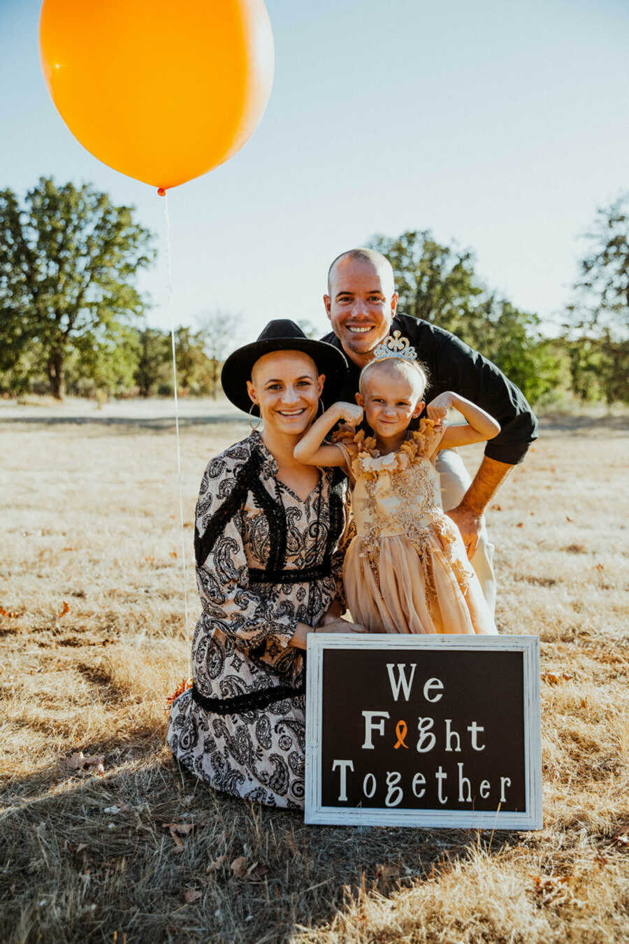 Family posing with daughter in grass field