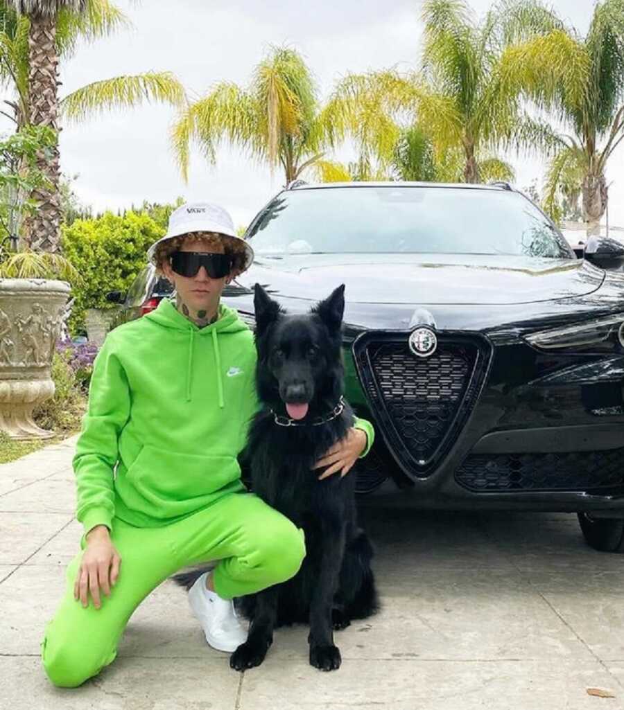 The Dog Daddy poses in the driveway with his black dog, Max.