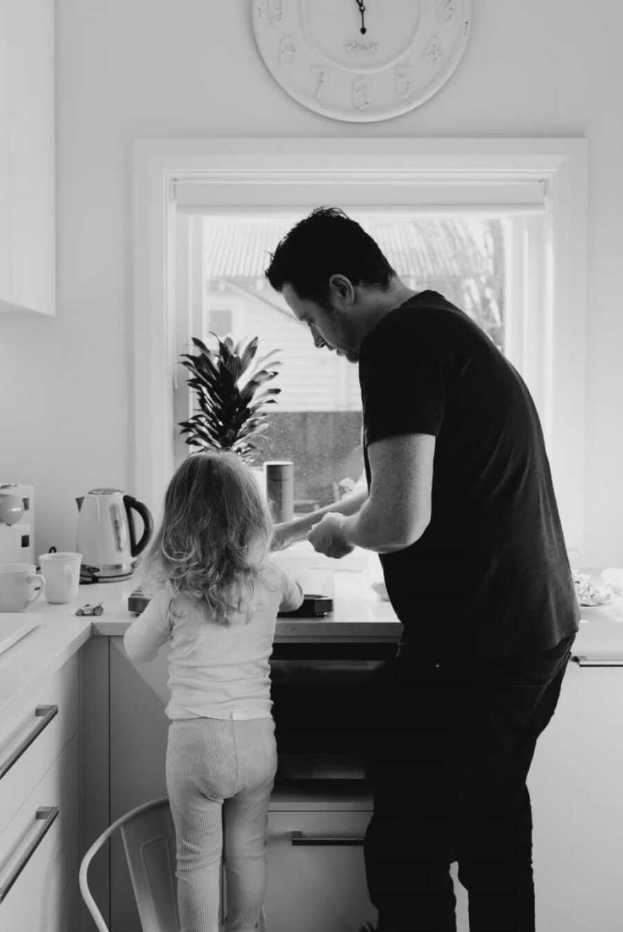 black and white photo of dad and daughter washing dishes in front of a window