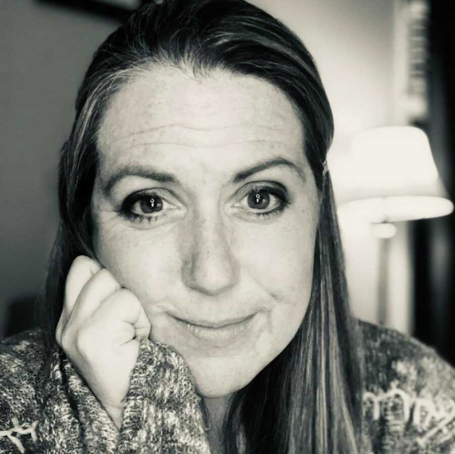 woman in a black and white photo while resting her chin on her hand