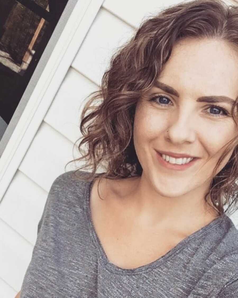 woman taking a selfie with a grey shirt on and freshly curled hair
