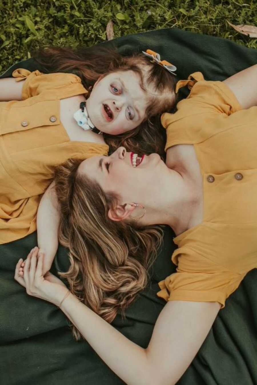 mom and daughter in matching yellow dresses on the ground posing