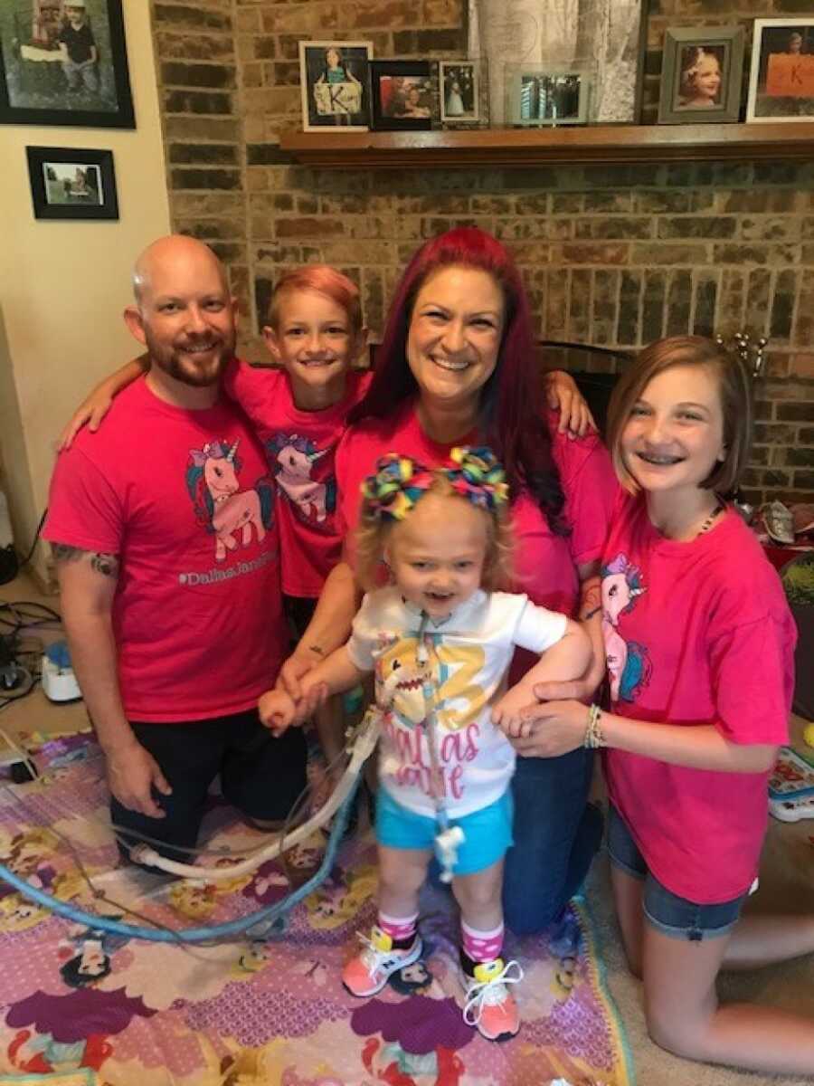 family photo in pink shirts in front of a fire place