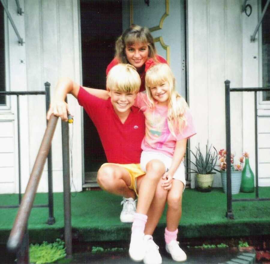 Mom with son and daughter pose in front of a house