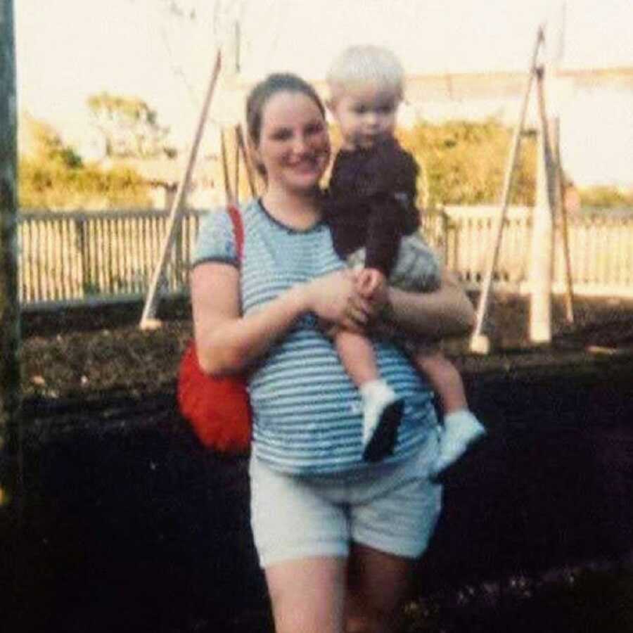 Pregnant mother holds toddler son in her arms 