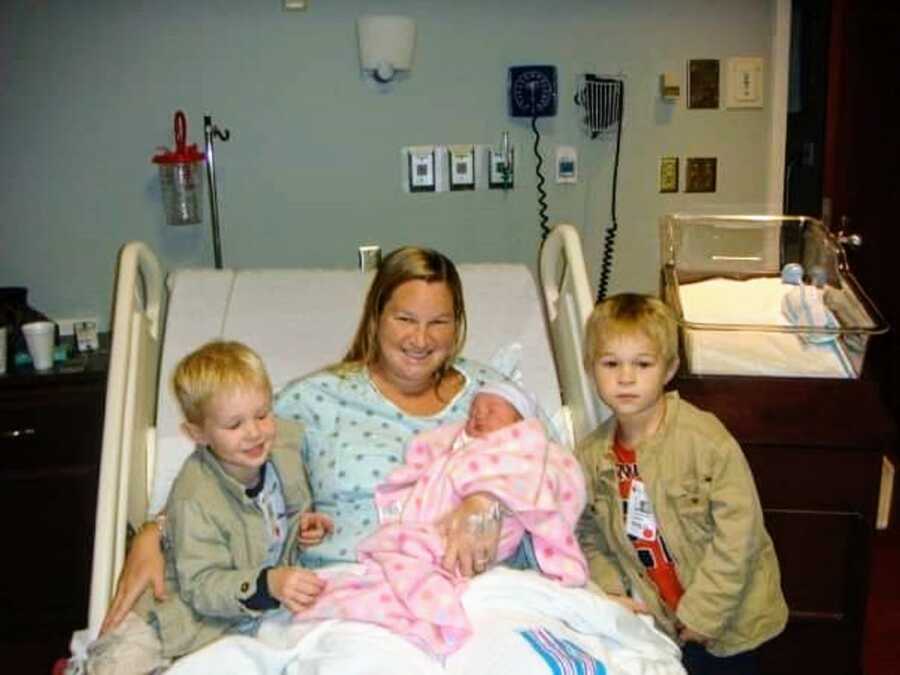 mother at the hospital holding newborn daughter and two sons