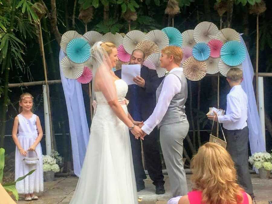 LGBT couple hold hands during their wedding ceremony