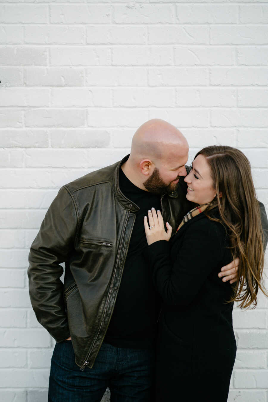 husband and wife holding each other close while taking a photo against a white back drop
