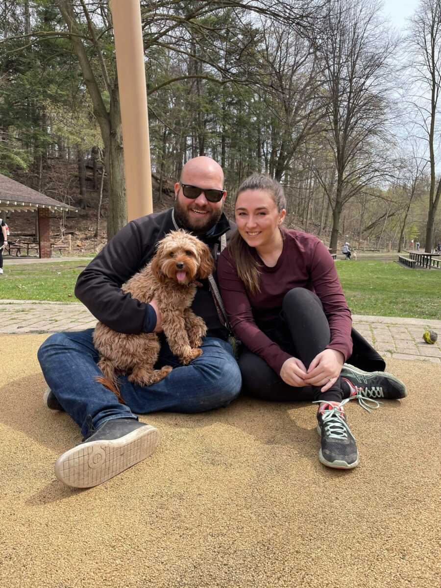 couple in a parking posing with their golden dog in their lap