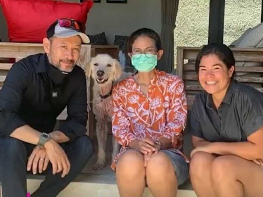 一家人坐在一起，戴着面具，带着被虐待的救援犬