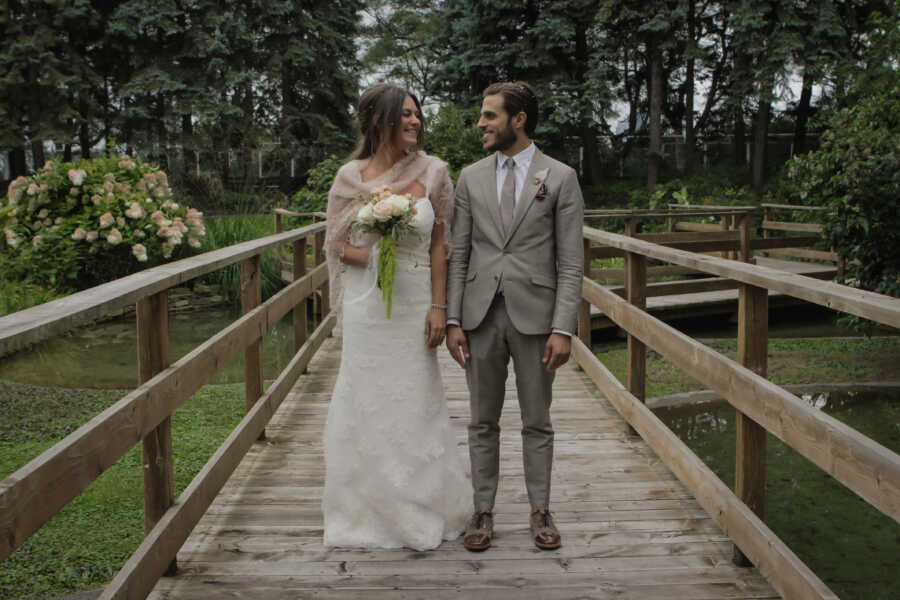 man and wife on their wedding day posing on a bridge