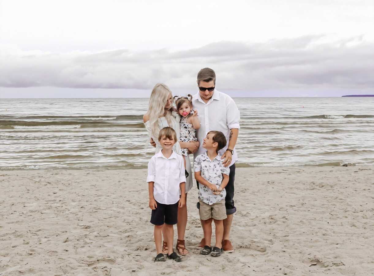 Family of five take photos together on the beach in matching outfits