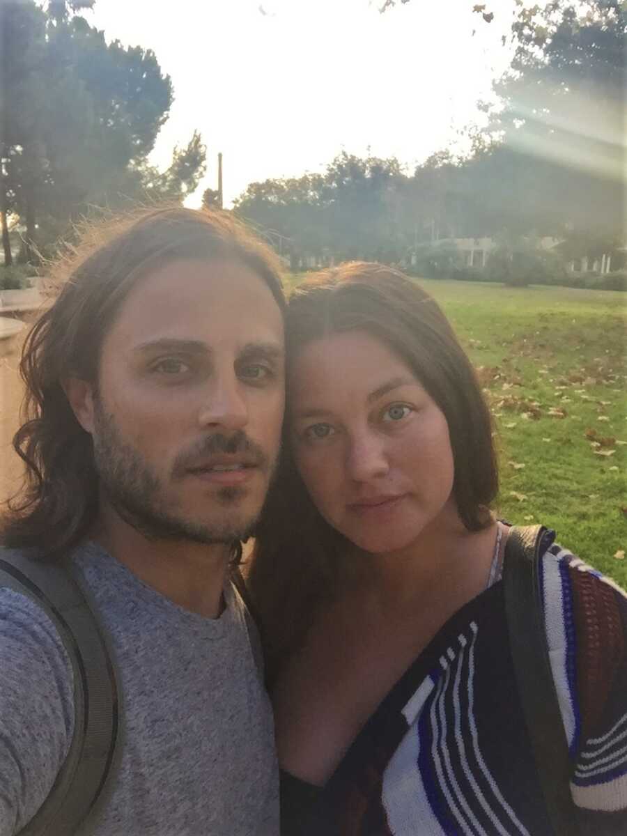 couple taking a selfie against the sun and green grass