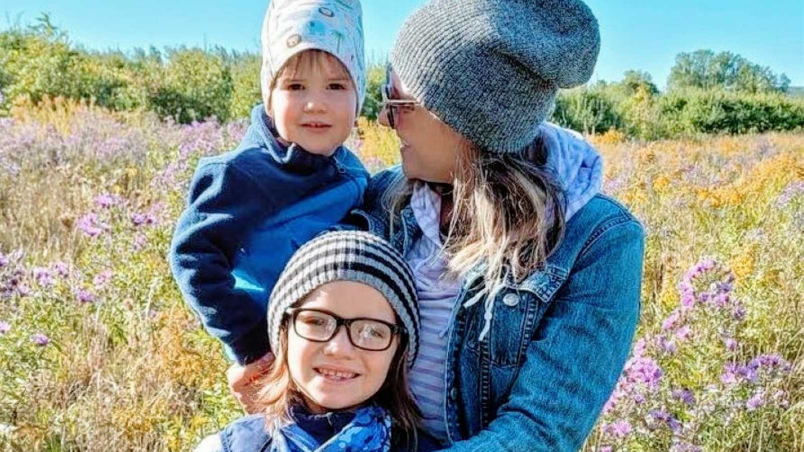 Mom takes a photo with her two sons in a field of flowers