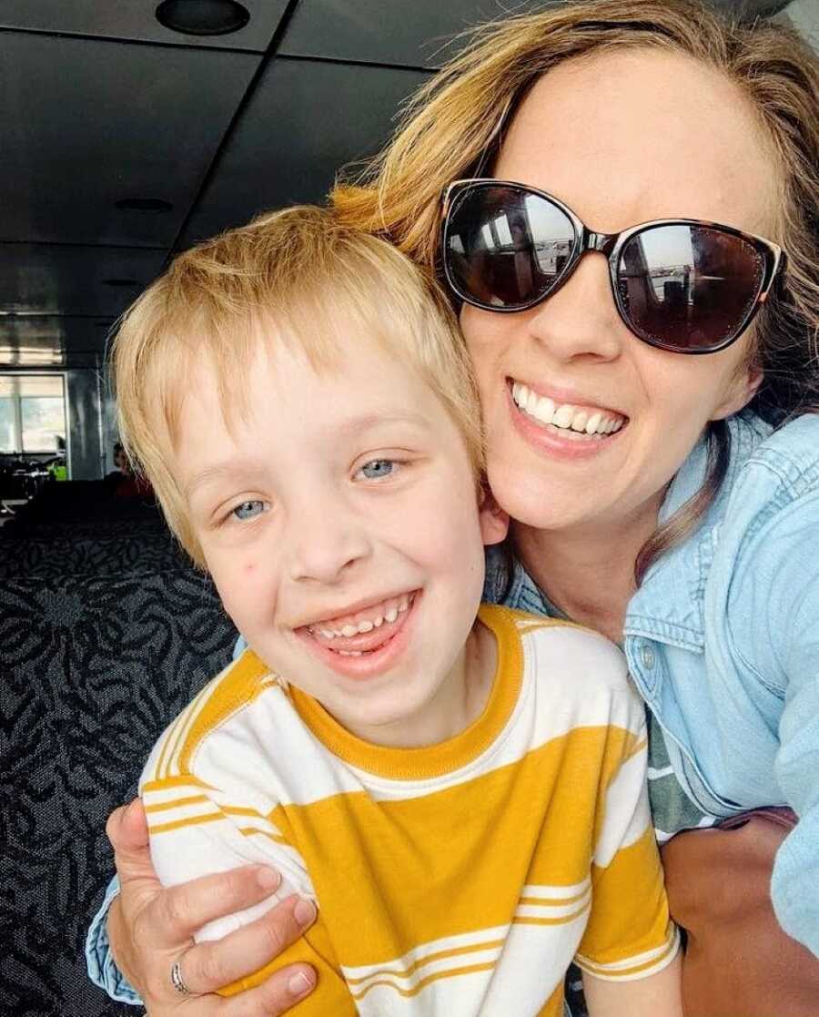 Mom takes a selfie with her young son with autism in a yellow and white striped shirt