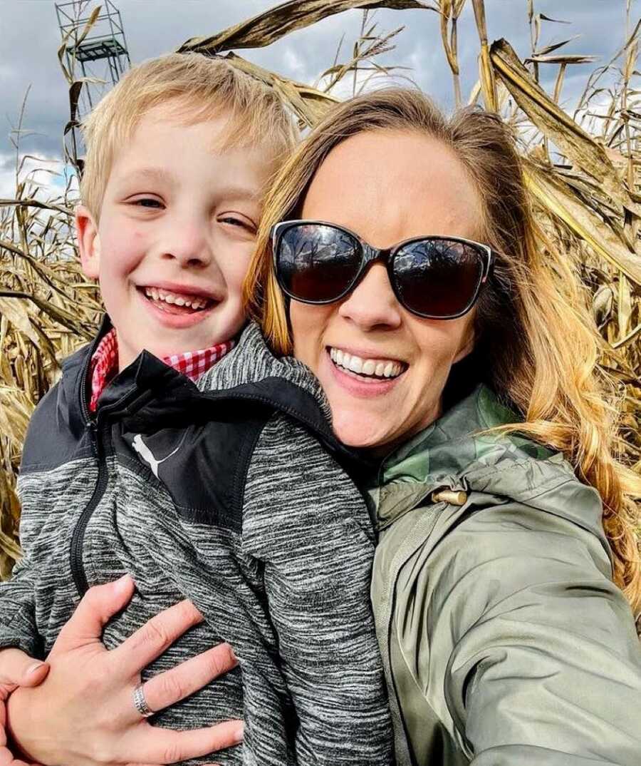 Mom hugs her son with autism while they participate in fall activities in a corn field