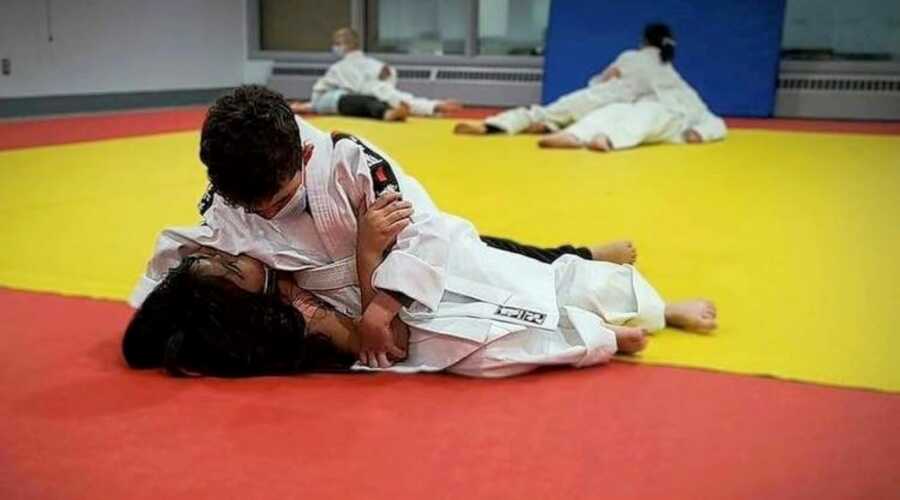 Mom takes a photo of her son practicing judo with another kid
