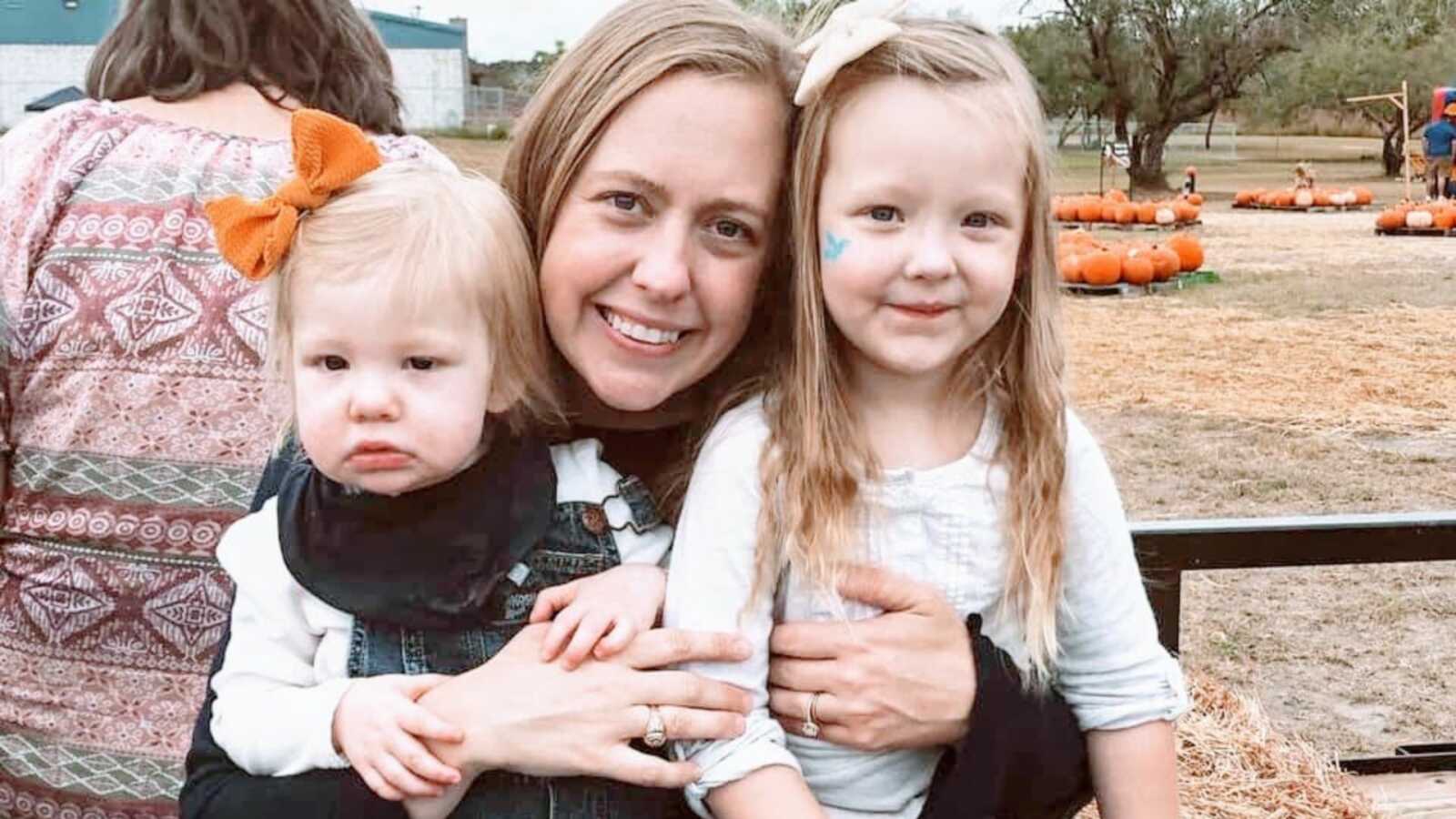 Special needs mom smiles with her daughters while on a hay ride at a pumpkin patch