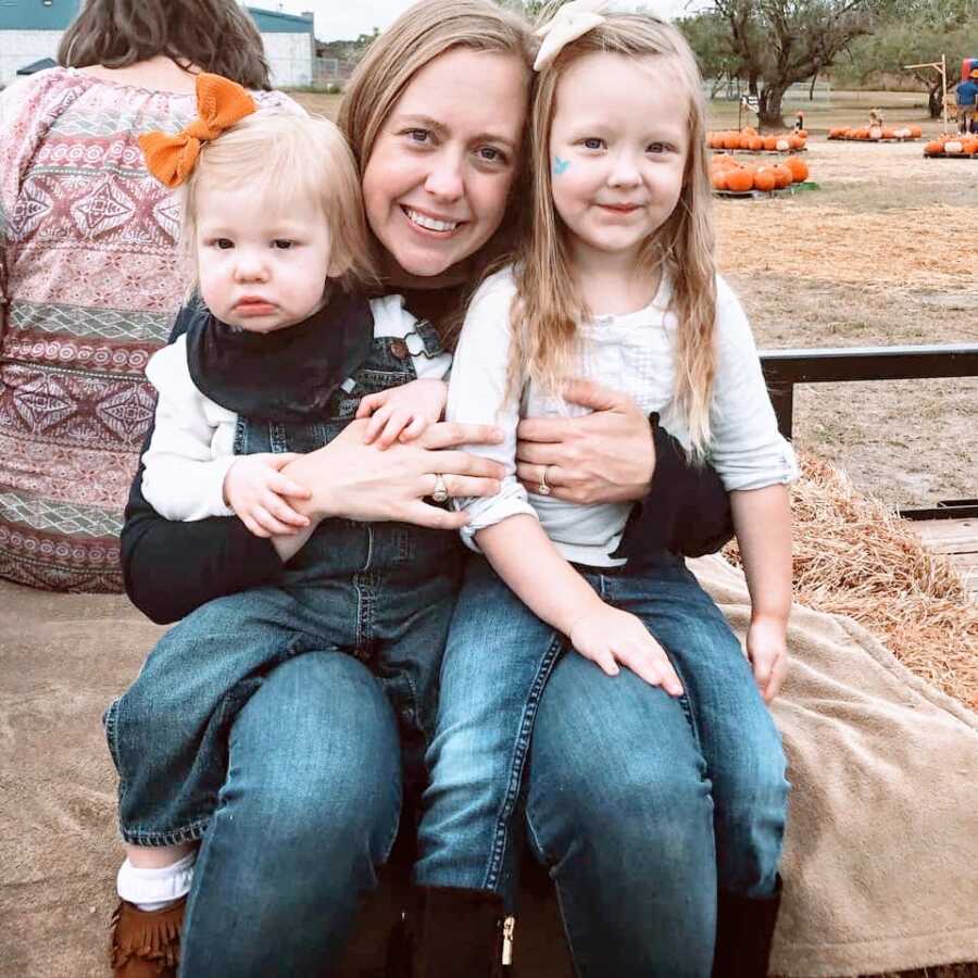 Special needs mom poses with her two daughters while on a hay ride, one with Coffin-Siris Syndrome