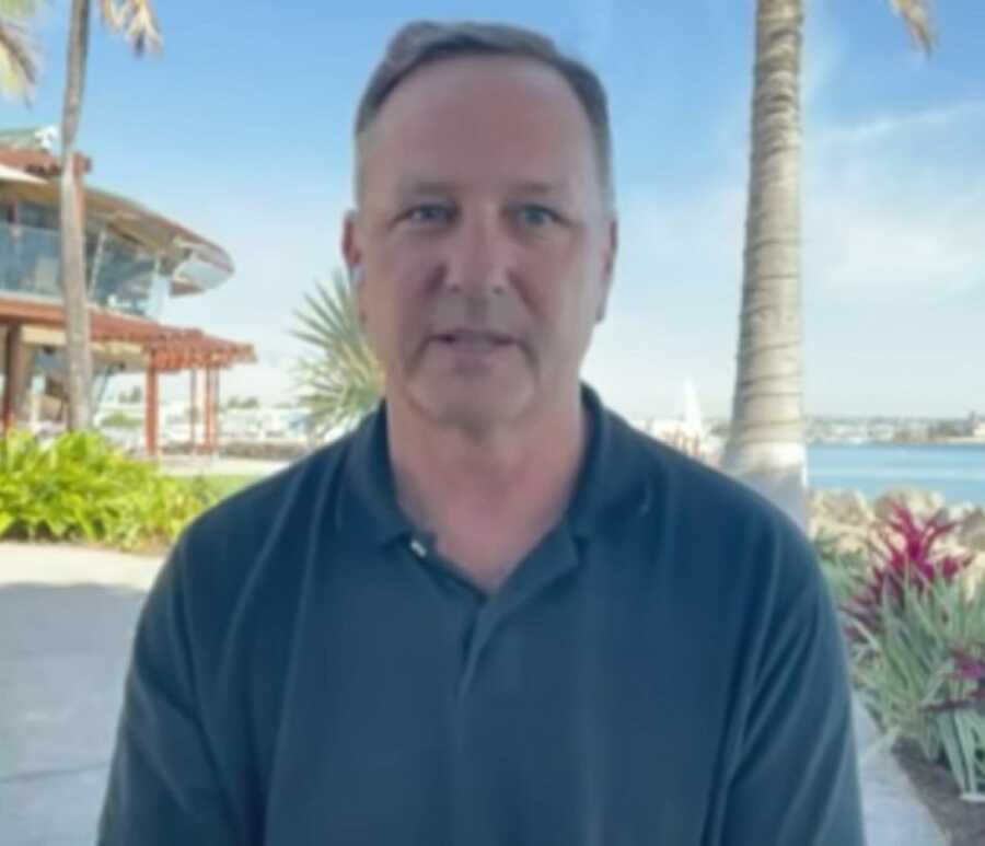 man who saved whale from a trap being interviewed in front of a palm tree 