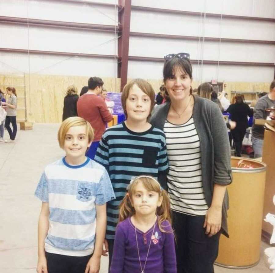 Mom takes a photo with her three children while at an event, all wearing striped shirts