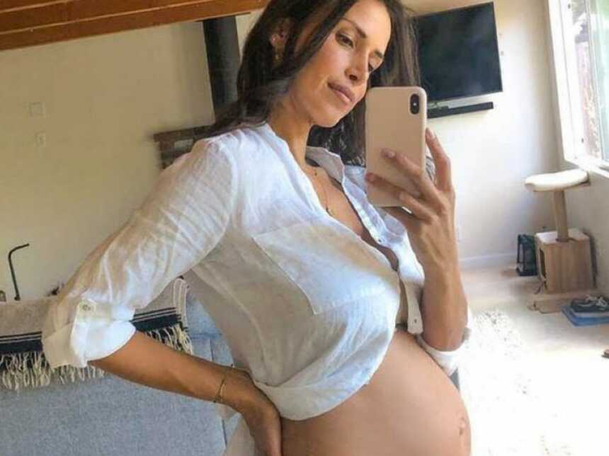 怀孕失败后，女人在镜子里炫耀她裸露的怀孕肚子
