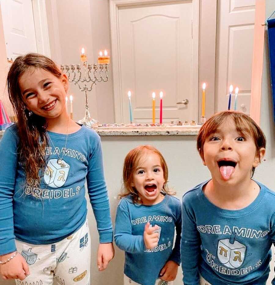 Three sisters take a silly photo together in matching Hanukkah pajamas with dreidels on them