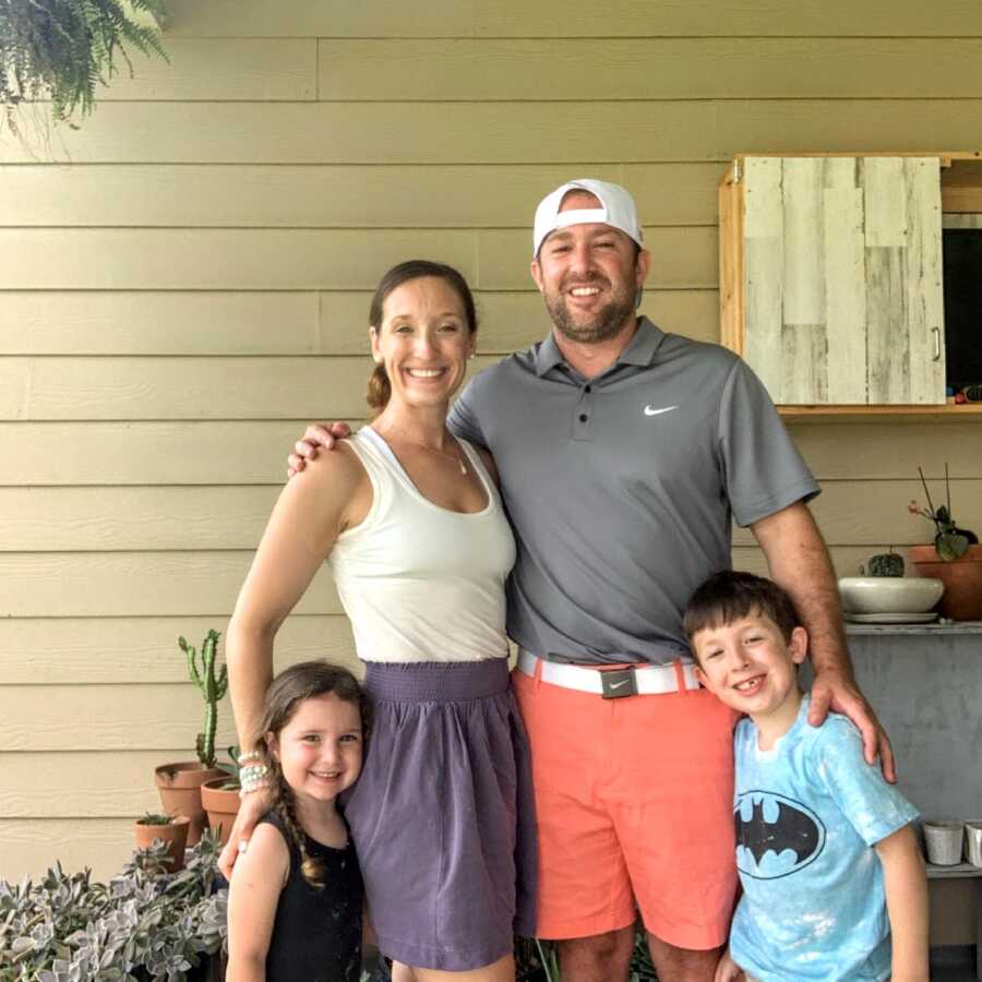 Family of four take a photo together on their front porch before a family outing