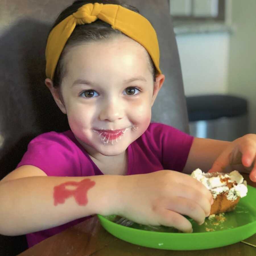 little girl in purple top enjoying apple muffins