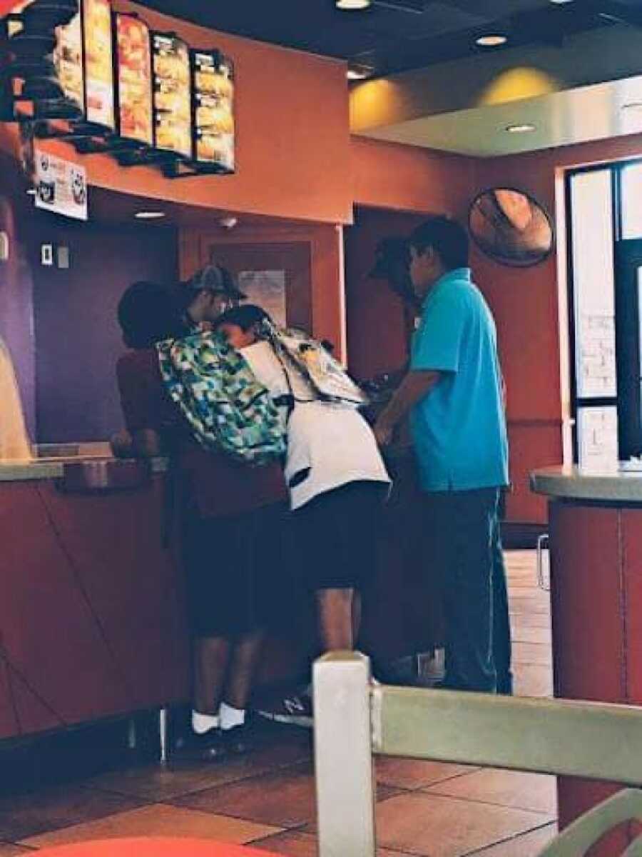 teen boys at the taco bell counter while the stranger pays for their taco