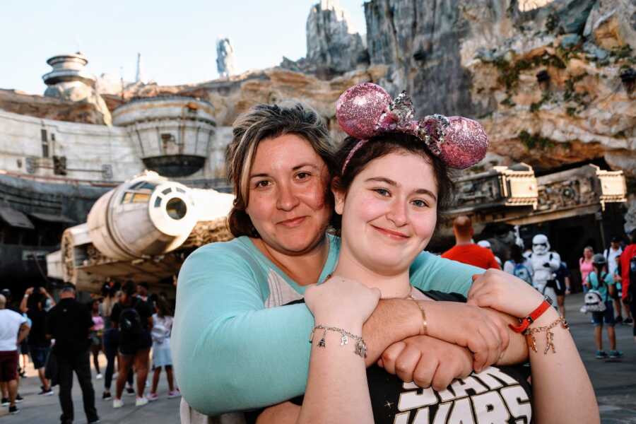 Mom poses with her daughter at Disneyland with Star Wars replicas behind them