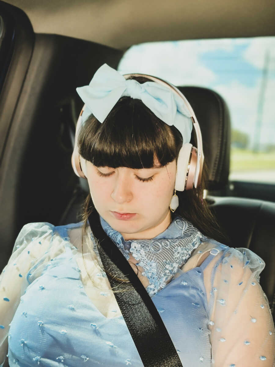 Young girl with epilepsy on her way to her surprise sweet 16 listens to music on headphones while dressed like Cinderella