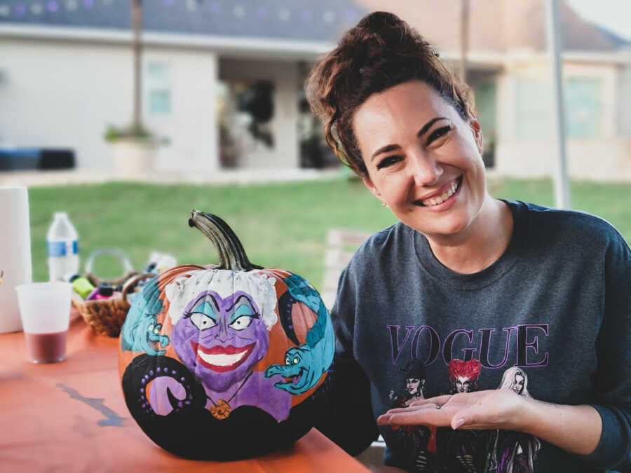 Woman paints Ursula from The Little Mermaid onto a pumpkin at a Halloween-themed Disney birthday party