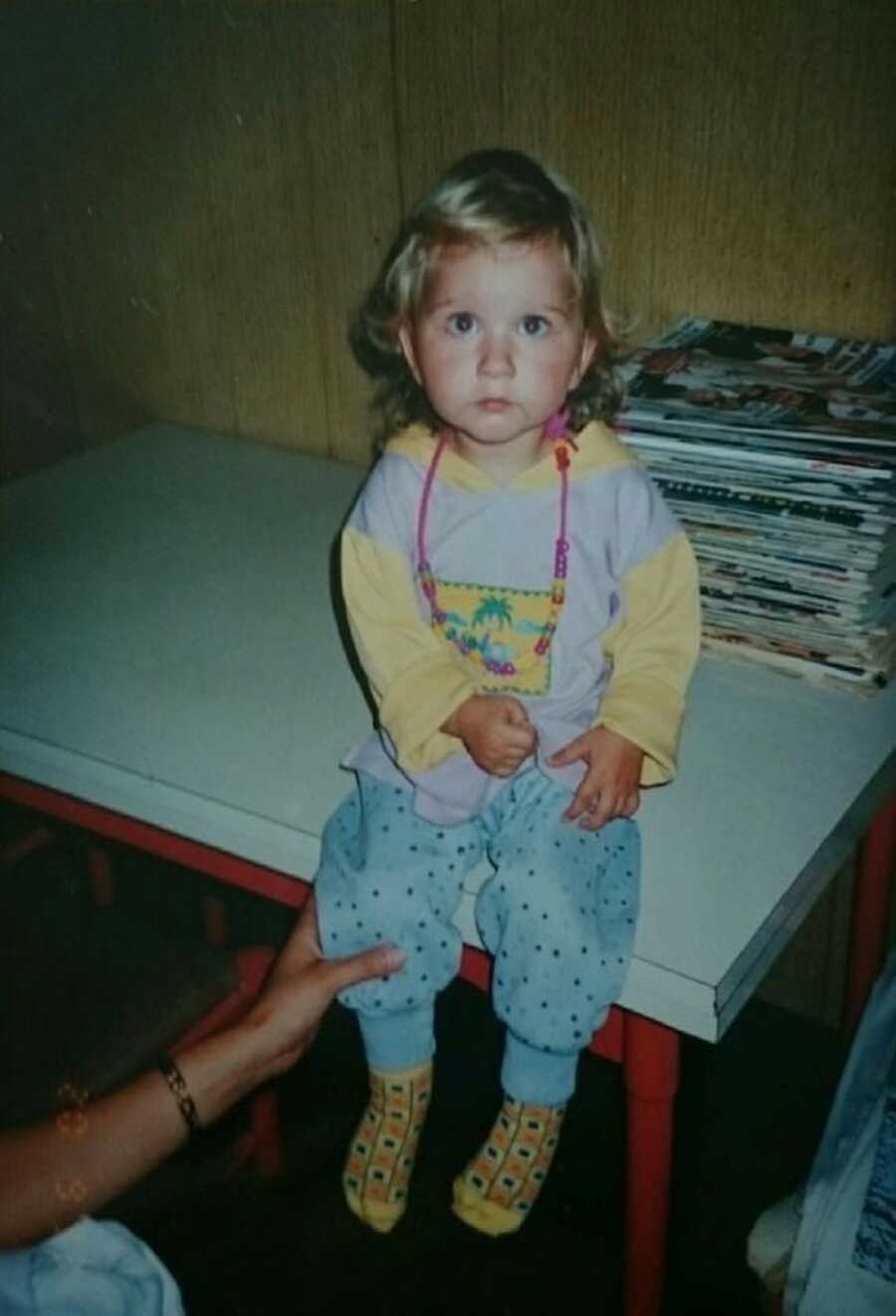 little girl sitting on a table taking a pic