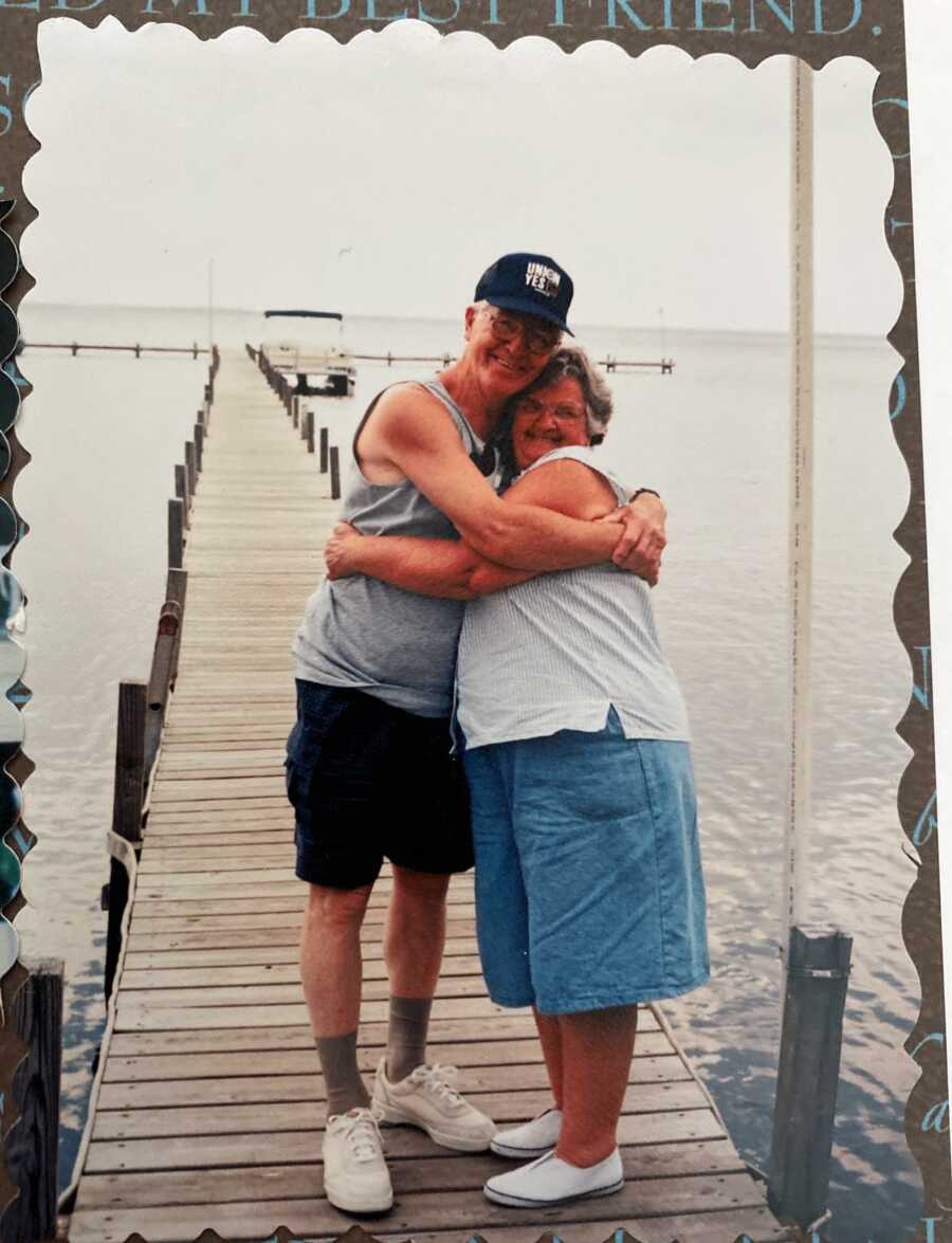 couple holding each other close on a pier by a lake