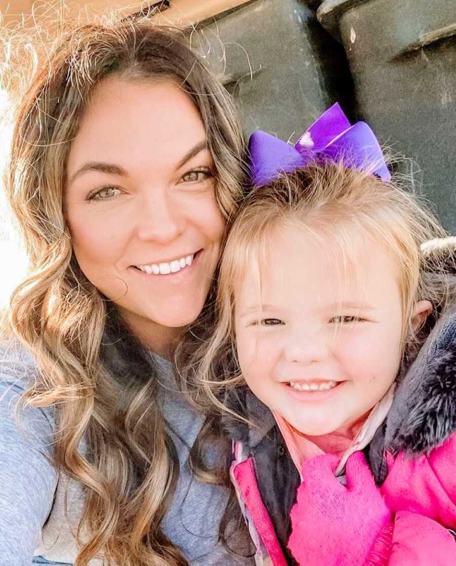 Mom takes a selfie with her oldest daughter while she wears a purple bow in her hair