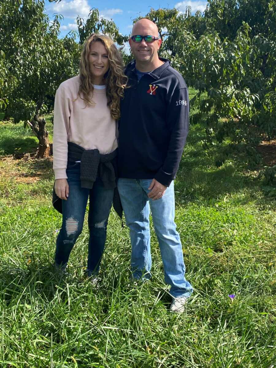 husband and wife taking a picture together in a field after wife's accident