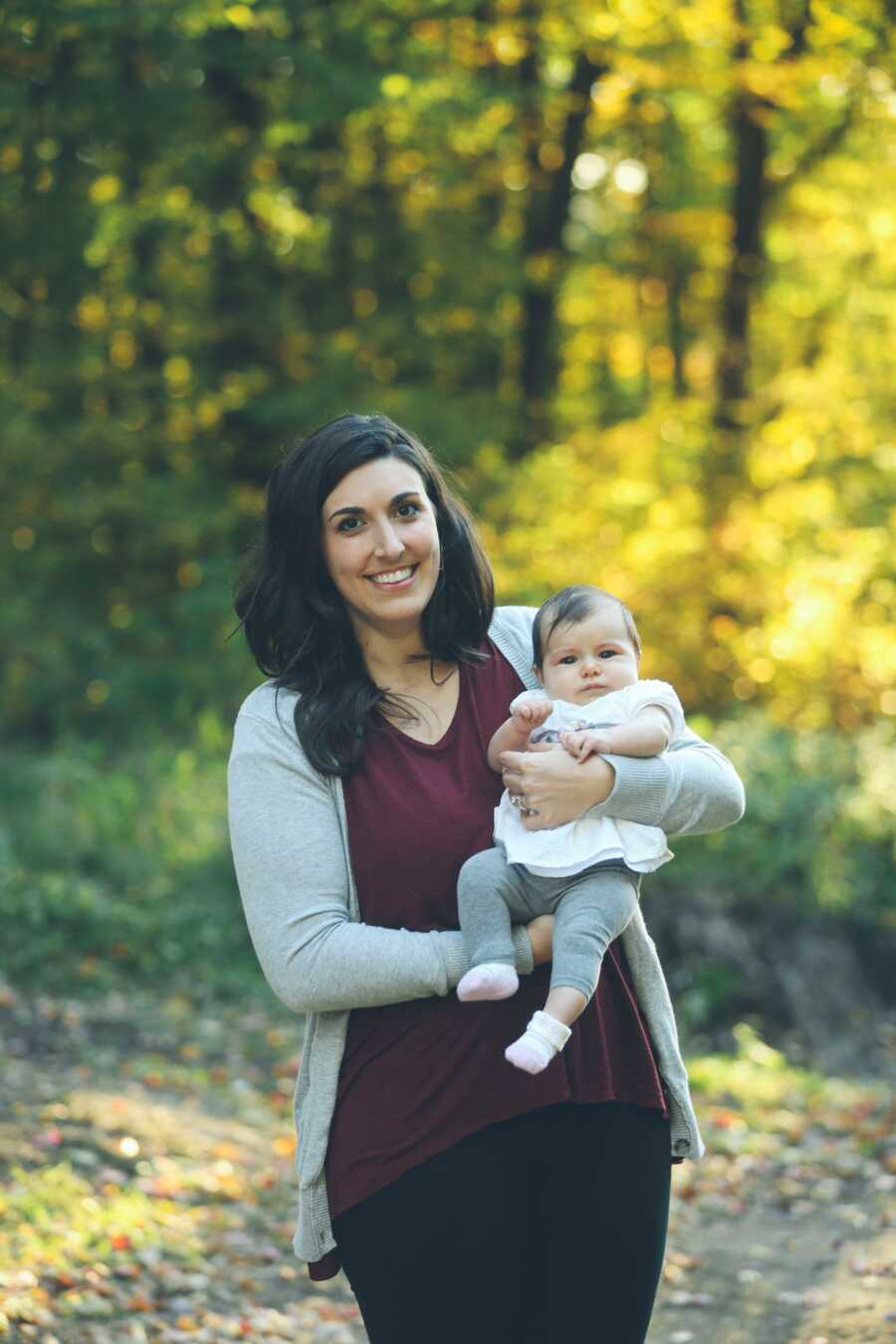 mother holding her daughter in an open field 