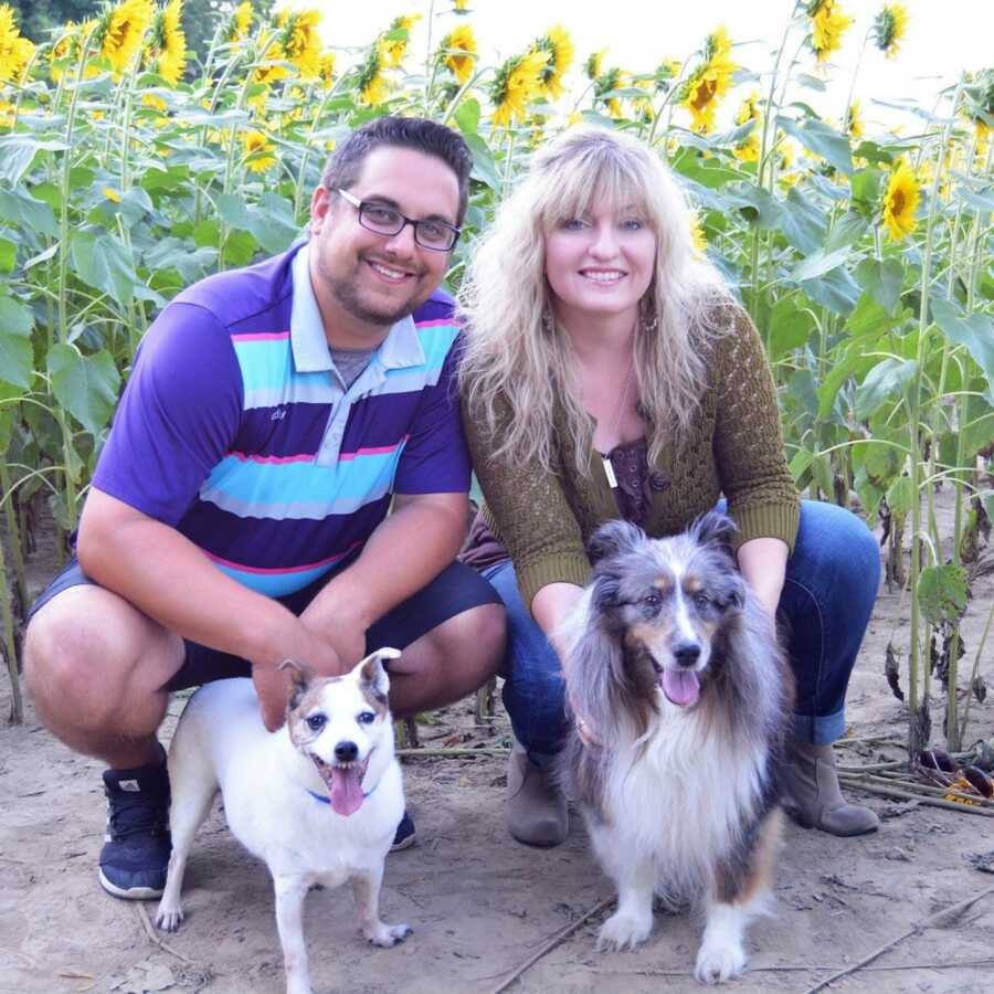 The Banion's and their dogs take a picture in front of a patch of sunflowers.