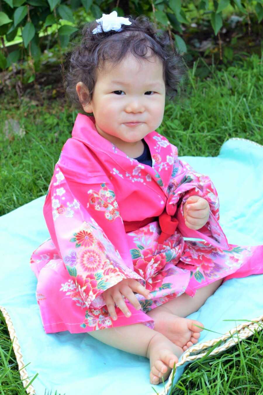 Everly sits on a blanket, wearing a traditional Japanese outfit. 