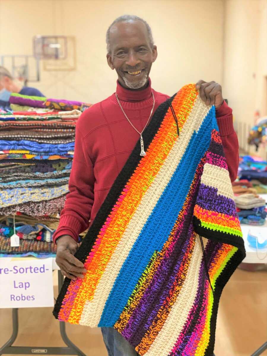 Larry holds up one of his crochet blankets. 