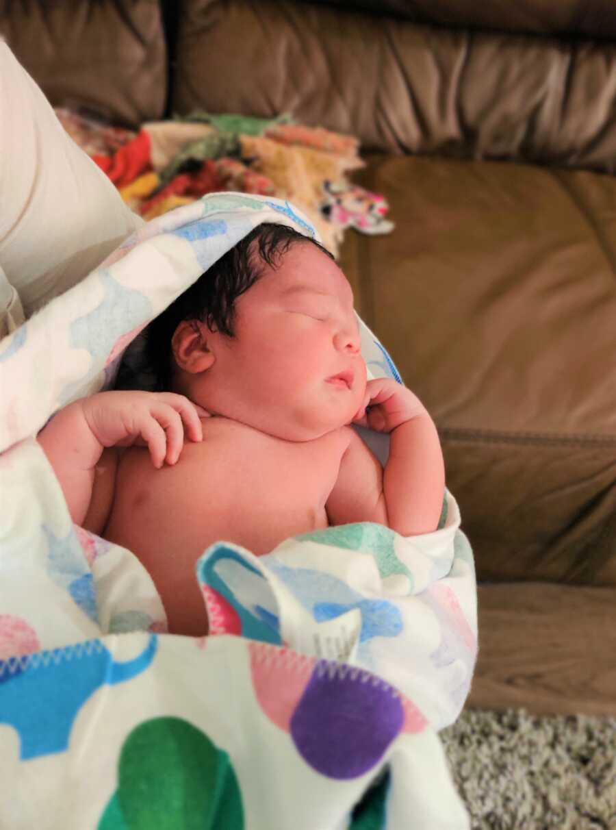 Newborn baby is wrapped in elephant blanket. 