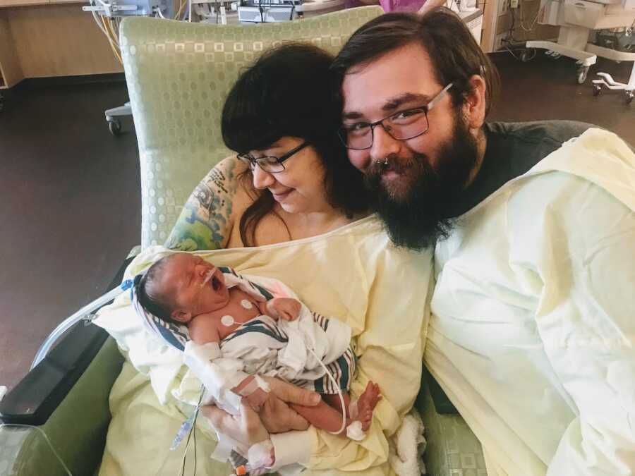 Mom holds newborn next to husband