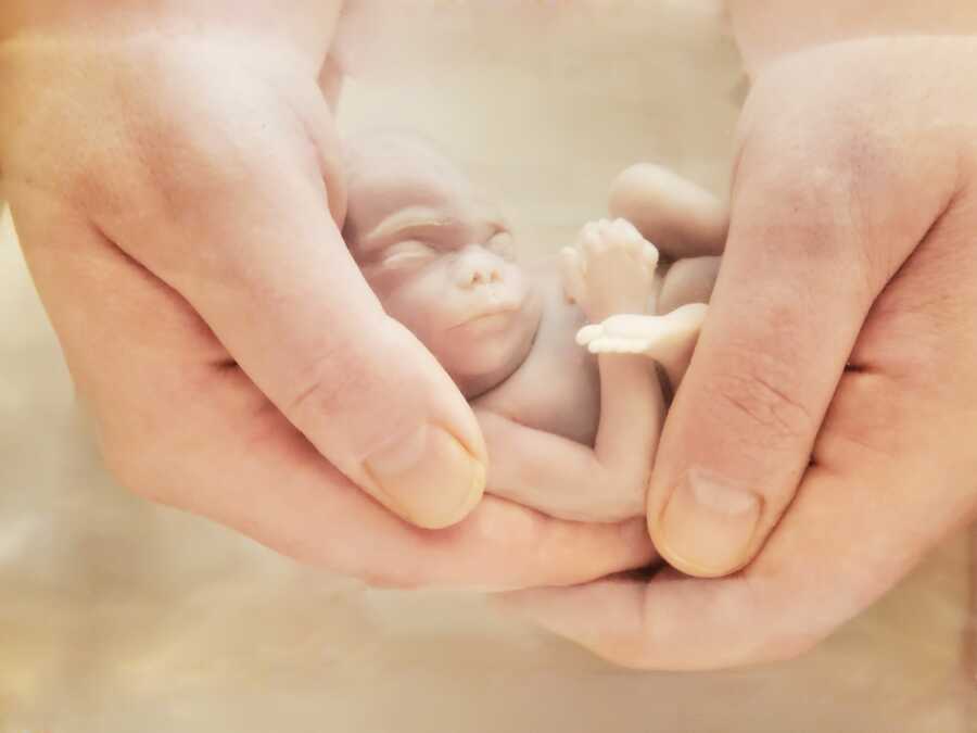 son taking pic of mom holding her daughter after birth