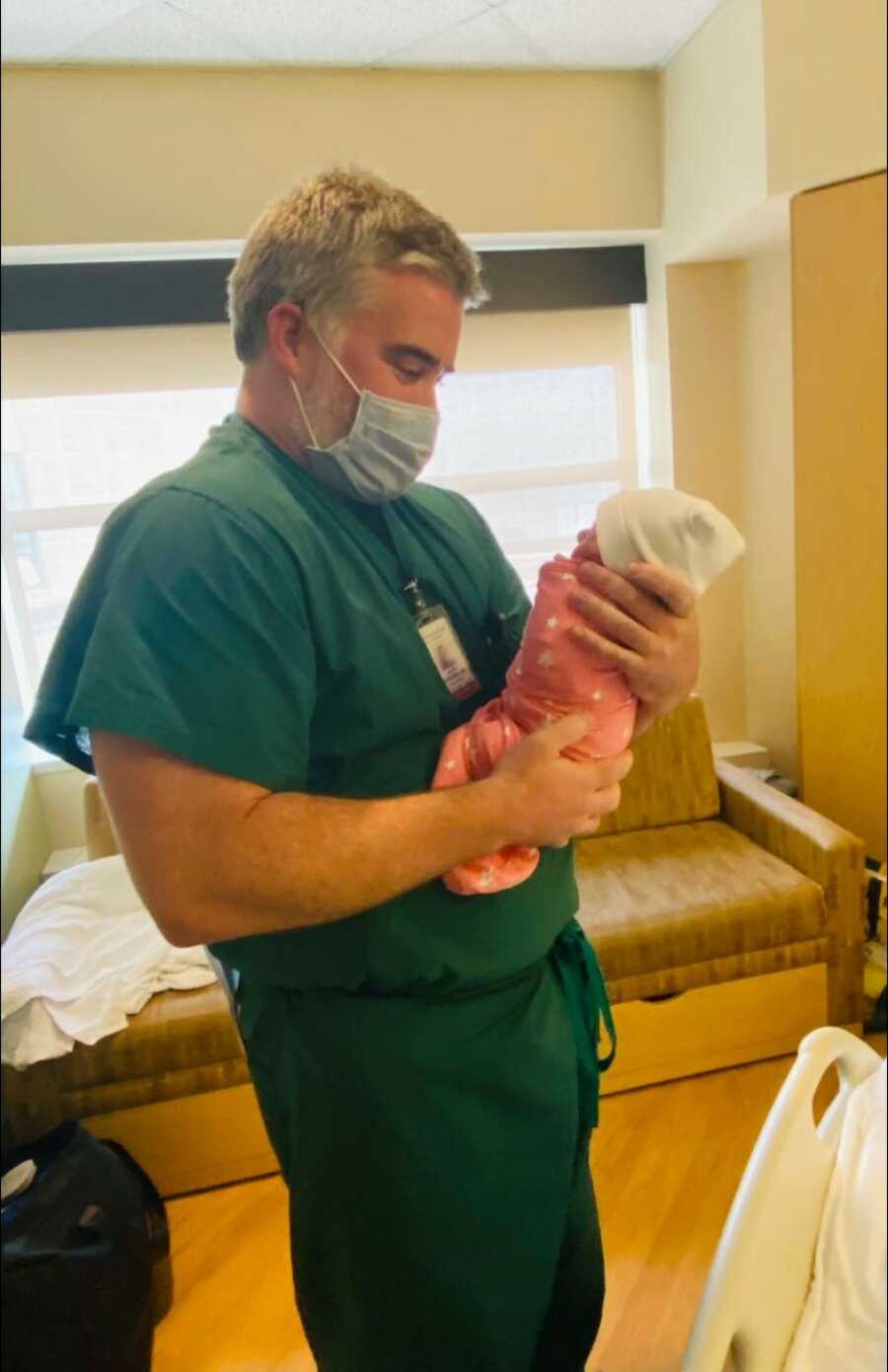 neonatologist holds baby girl to the same family he helped while they lost their son before her