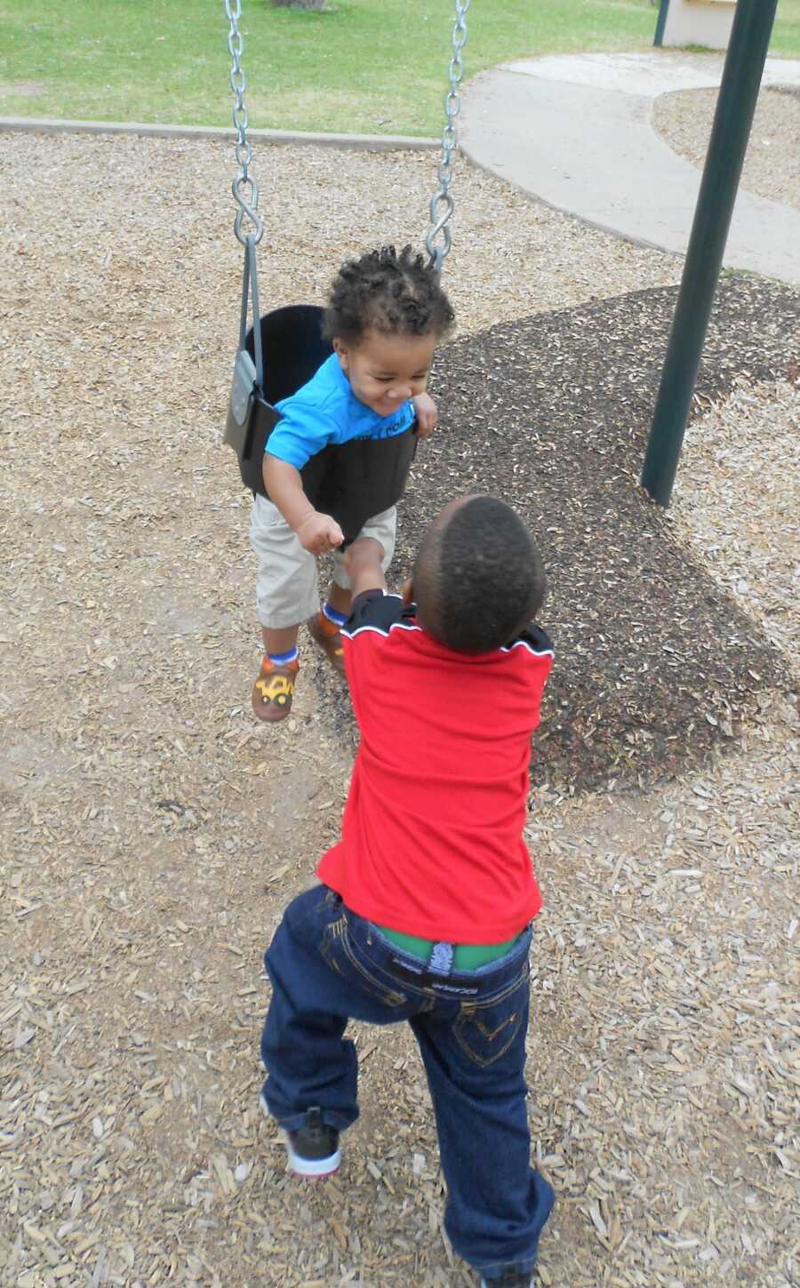 Emma's younger, adopted siblings play on the swings. 