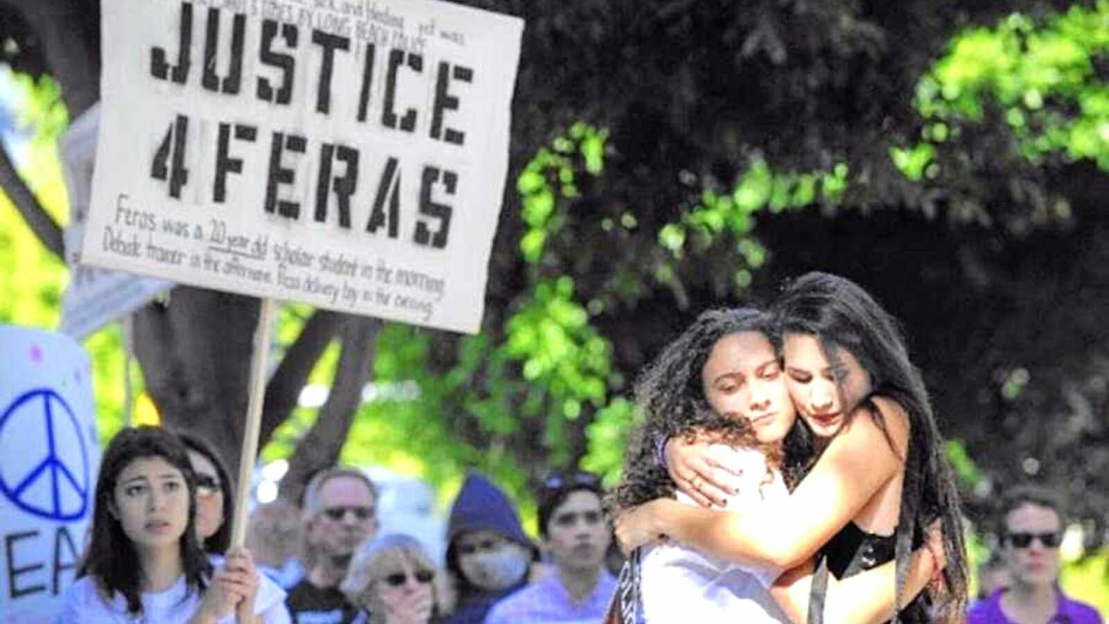 Two women hug at a rally for social justice